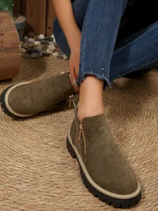 Bottines en daim vert olive avec fermeture éclair et semelle épaisse portées par un mannequin