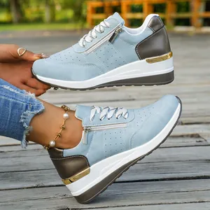 Detail view of light blue platform sneakers with side zipper and gold trim on foot.