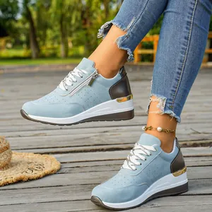 Detailed view of women's blue wedge sneakers featuring a side zipper and gold trim