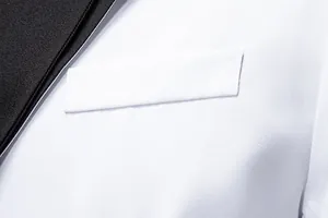 Macro detail of men's white suit jacket featuring black lapel and chest pocket