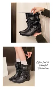 Gros plan de bottes slouchy noires de style western avec rivets et boucles argentées.