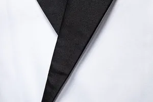 Close-up detail of a modern black lapel on a white slim fit tuxedo jacket for men.
