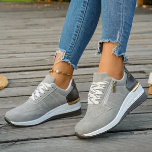 Grey women's platform sneakers with gold accents and side zipper detail on a wooden floor