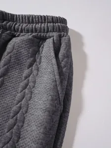 Dettaglio ravvicinato della fascia trapuntata e della tasca di un pantalone jogger grigio.