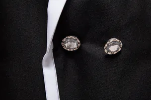 Close-up of sparkling rhinestone buttons and white piping detail on a black suit jacket