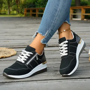 Close-up of black women's platform sneakers with white laces and side zipper detail.