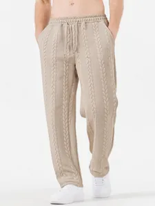 Dettaglio dei pantaloni da uomo beige in maglia a trecce con coulisse e gamba larga.