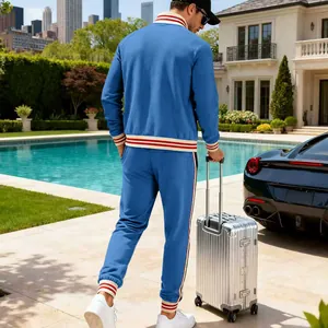 Back view of men's blue heavy fleece tracksuit with red striped cuffs by a luxury pool area