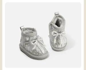 Detailed macro view of sparkly silver girls' winter snow boots with a pearl bow accent