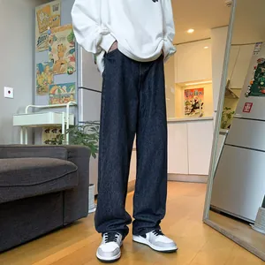 Detailed view of men's loose straight-leg dark denim jeans styled with sneakers