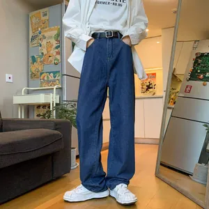 Detail view of men's loose straight-leg denim jeans in a lifestyle home setting