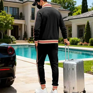 Back view of a premium black men's tracksuit with striped ribs in a luxury villa setting