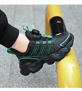 Close-up of kids black sneakers with green accents and rotating buckle closure system.