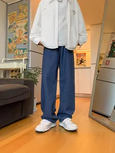 Stylish loose fit dark blue men's straight denim jeans in a casual indoor setting