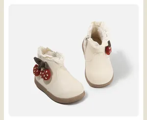 Detailansicht cremefarbene Kleinkinderschuhe mit Spitzenbesatz und Erdbeer-Anhängern