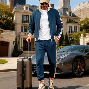 Full body view of a man wearing a navy blue heavyweight fleece tracksuit by a supercar