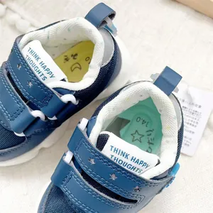 Close-up detail of navy blue toddler shoes with velcro straps and slogan embroidery