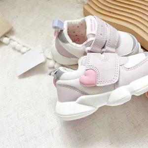 Macro view of pink toddler walking shoes featuring a cute heart and velcro straps