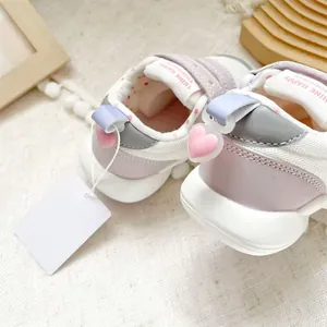 Close-up of pink toddler shoes showing the heel heart charms and velcro text straps