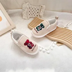 Detail of children's slip-on canvas shoes featuring cute embroidered cartoon bears.