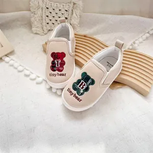 Close-up detail of children's canvas slip-on shoes featuring cute tiny bear embroidery