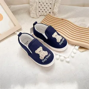 Detail of children's navy blue slip-on canvas shoes with cute cartoon bear embroidery