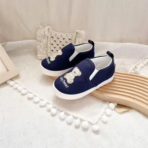 Detail of navy blue children's slip-on canvas shoes with tiny bear embroidery