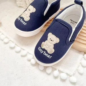 Detailed macro view of navy blue children's canvas slip-on shoes with cute bear embroidery
