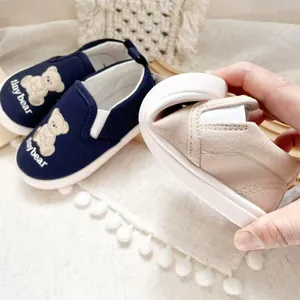 Close-up showing the flexible rubber sole of a cartoon bear children's canvas slip-on shoe.