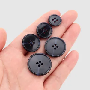 Set of premium navy blue resin buttons for clothing in multiple sizes held in hand