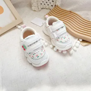 Detailed view of white toddler sneakers with cherry pattern and velcro straps