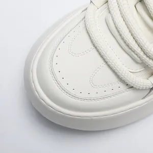 Detailed close-up view of the rounded toe and thick woven laces on white chunky sneakers.