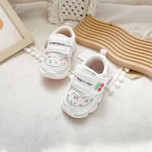 Detailed view of white toddler walking shoes with cute cherry patterns and velcro straps.