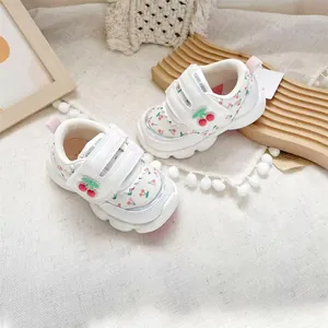 Detail view of white toddler walking shoes with cute cherry patterns and velcro straps