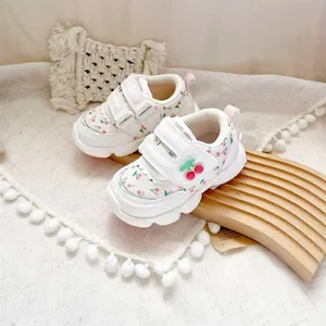 Detail of white baby walking shoes with cute cherry print and velcro straps