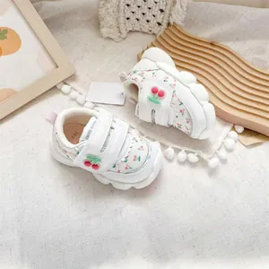Close-up of white baby walking shoes with cute cherry patterns and velcro straps