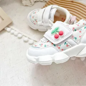 Detailed close-up of cute cherry pattern and velcro strap on white baby walking shoes