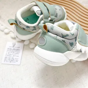 Detailed view of mint green baby walking shoes with cute dinosaur pattern and Velcro straps