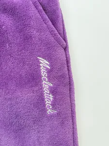 Detailed view of embroidered Muscleattack logo on soft purple coral fleece fabric
