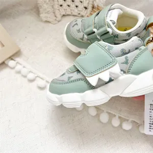 Close-up of mint green baby walker shoes featuring dinosaur tooth detail and velcro straps.