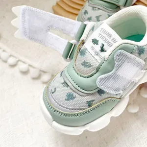 Close-up of mint green toddler walking shoes with dinosaur prints and velcro straps