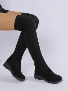 Detalle de botas calcetín negras por encima de la rodilla con punto de ochos y cuña