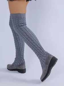 Vista detallada de botas altas de punto gris con un diseño de patrón de trenzas