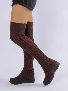 Primer plano de la textura de punto trenzado y la suela de cuña de estas botas altas