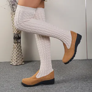 Primer plano de botas de cuña por encima de la rodilla de punto trenzado crema y ante