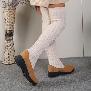 Detalle de las botas mosqueteras de cuña en ante marrón con parte superior de punto crema