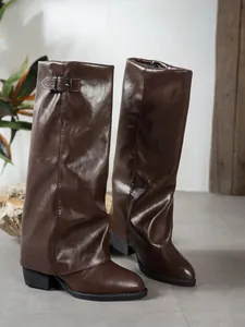Close-up view of dark brown pointed-toe slouchy boots featuring a decorative metal buckle