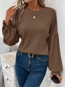 Close-up of a women's brown ribbed knit long sleeve sweater with ruffled cuffs and round neck