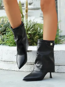 Detailed shot of elegant black pointed toe pant leg boots with high stiletto heels and buckles
