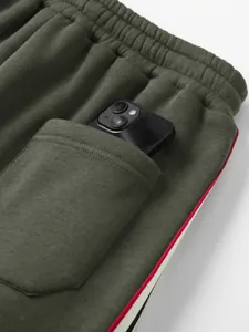 Nahaufnahme der funktionellen tiefen Seitentasche an olivgrünen Joggern mit einem Smartphone